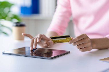 Tablet bilgisayar ve kredi kartı kullanan bir kadın kredi kartıyla alışveriş yapıyor. İnternetten öde İnternetten al. İnternet bankacılığına göre ödeme.
