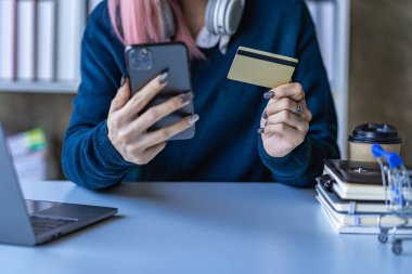 Kadın internet üzerinden akıllı telefondan alışveriş yapıyor kredi kartı ödemesi internet üzerinden alıyor, internet bankacılığıyla ödüyor.