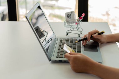 Asyalı bir kadın internetten bilgisayarla alışveriş yapıyor ve internetten kredi kartıyla alışveriş yapıyor. İnternet üzerinden alışveriş yap. İnternet bankacılığına göre ödeme