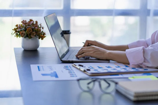 stock image hand of business woman hold smartphone use analyzing and calculating the annual income and expenses, a financial chart and financial report, technology and bussiness concept.