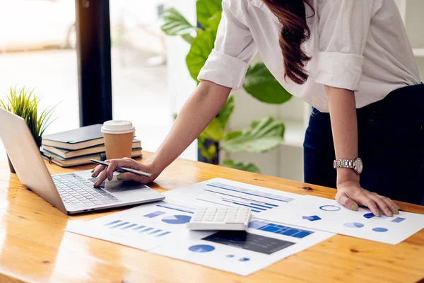 stock image hand of business woman hold smartphone use analyzing and calculating the annual income and expenses, a financial chart and financial report, technology and bussiness concept.