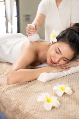 Güzel genç Asyalı kadın spa ortamında masaj yaptırıyor, geleneksel aromaterapi ve güzellik terapisi, yakın plan fotoğraf..