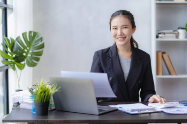 İş planlama ofisinde çalışan profesyonel Asyalı kadın muhasebeci muhasebe satış raporlarını gözden geçiriyor. Bilgisayarda çalışan finans analisti, online iş kavramı.