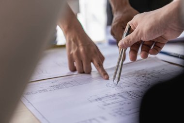 İnşaat şantiyesi mühendisleri, iki işadamı, mühendislik objeleri birbiriyle etkileşen ortaklar, müteahhitler ve mimarlarla birlikte dizüstü bilgisayardaki planlara bakıyorlar ve proje üzerinde çalışma hakkında konuşuyorlar.
