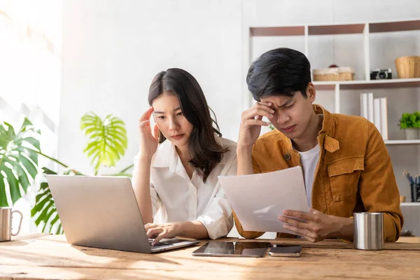 Business couple and successful business asian woman work together in the morning with laptop and paperwork discussing home finances.