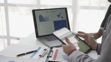 Asyalı işadamı, iş yerindeki bir ekiple fikir paylaşımı ve iş analizi yapıyor. Turta grafikleri ve istatistiklerle belgeleri paylaşıyorlar. 