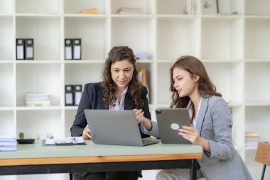 İş kadını ve muhasebeci laptop ve tabletle konuşuyor. İki bin yıllık Kafkasyalı iş kadını ofiste birlikte bir proje planlıyor.