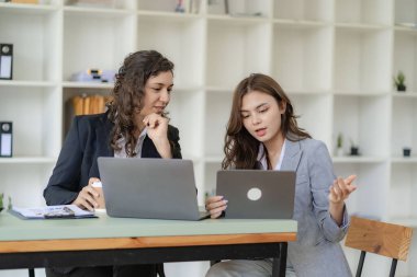 İş kadını ve muhasebeci laptop ve tabletle konuşuyor. İki bin yıllık Kafkasyalı iş kadını ofiste birlikte bir proje planlıyor.