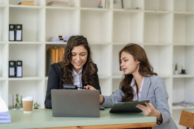 İş kadını ve muhasebeci laptop ve tabletle konuşuyor. İki bin yıllık Kafkasyalı iş kadını ofiste birlikte bir proje planlıyor.