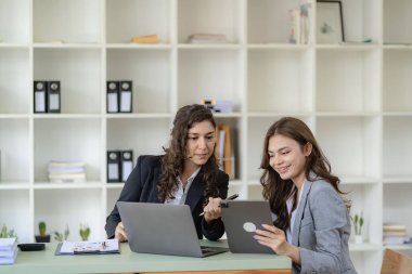 İş kadını ve muhasebeci laptop ve tabletle konuşuyor. İki bin yıllık Kafkasyalı iş kadını ofiste birlikte bir proje planlıyor.
