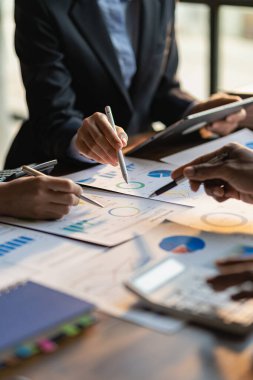 Hesap makinesi kullanarak iş ekibi toplantısı. Çizelgelerle çalış ve iş stratejilerini analiz et. finansal istatistikler masadaki dikey görünümde oturuyor