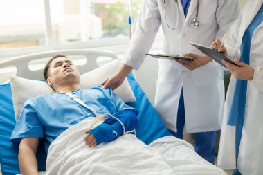 İki doktor hastanede salin solüsyonu alırken yatakta yatan bir hastayla konuşuyor. Profesyonel tıbbi servis konsepti. Hasta Stok Resmini rahatlatan dikkatli bir doktor.