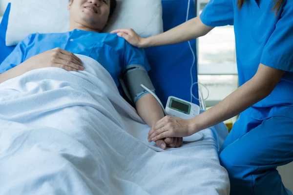 stock image Two doctors talking to a patient lying in bed while receiving saline solution in hospital Professional medical service concept Attentive doctor comforting a patient Stock Picture