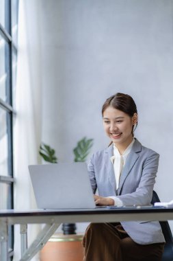 Ofiste dizüstü bilgisayarda çalışan genç bir kadın, iş yerinde çalışan Asyalı bir muhasebeci, evde finansal belgelerle çalışan güzel serbest çalışan bir kız. dikey resim