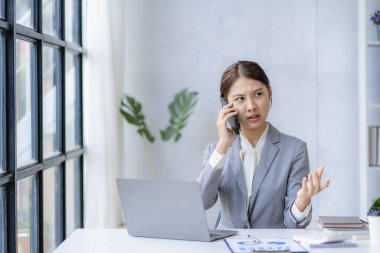 Gülümseyen Asyalı kadın müşteriyle konuşuyor. Genç, pozitif kadın muhasebeci akıllı telefon kullanıyor. Masasındaki ekiple konuşuyor.