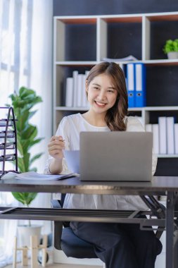 Ofiste dizüstü bilgisayarda çalışan genç bir kadın, iş yerinde çalışan Asyalı bir muhasebeci, evde finansal belgelerle çalışan güzel serbest çalışan bir kız. dikey resim