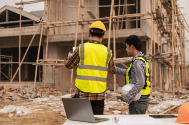 İnşaat mühendisleri, yönetim ekibiyle iletişim kurmak için telsiz kayıtlarını inceliyor. Mühendis, inşaat alanındaki inşaat fikirlerini denetlemesi için ev yapımını önerdi.