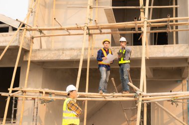 İnşaat mühendisleri, yönetim ekibiyle iletişim kurmak için telsiz kayıtlarını inceliyor. Mühendis, inşaat alanındaki inşaat fikirlerini denetlemesi için ev yapımını önerdi.