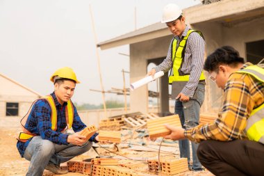 İnşaat mühendisleri, yönetim ekibiyle iletişim kurmak için telsiz kayıtlarını inceliyor. Mühendis, inşaat alanındaki inşaat fikirlerini denetlemesi için ev yapımını önerdi.