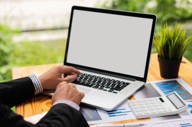 Piyasa grafiğini işaret eden bir kalem tutan işadamı, ofis finans kavramında matematik için hesap makinesi kullanarak bilgisayarla çalışıyor. Resimleri kapat.