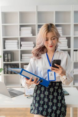 Asyalı genç bayan çalışan akıllı telefon kullanarak müşterilere danışmanlık yapıyor. İş danışmanlığı kavramı dikey görüntü.