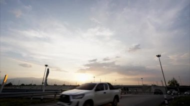 Zaman atlamalı bulutlar, gece karanlığında gökyüzünde hızla hareket eder. Arabalar, gece araba ışıklarıyla aydınlanan bir köprüde yol alır..