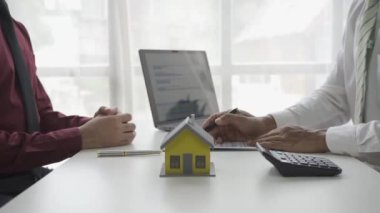 Emlakçı erkek müşteriyle el sıkışıyor. İş adamı ev kredisi projesi 4K 'nın modelini gösterdikten sonra satılığa çıkmayı kabul ediyor.