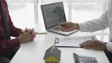 Emlakçı erkek müşteriyle el sıkışıyor. İş adamı ev kredisi projesi 4K 'nın modelini gösterdikten sonra satılığa çıkmayı kabul ediyor.