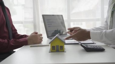 Emlakçı erkek müşteriyle el sıkışıyor. İş adamı ev kredisi projesi 4K 'nın modelini gösterdikten sonra satılığa çıkmayı kabul ediyor.