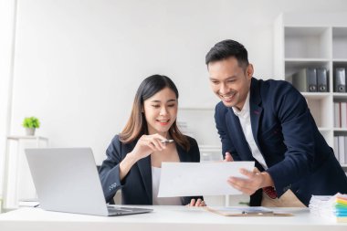 Zeki ve profesyonel erkek yönetici, bayan asistanıyla çalışıyor. Mali raporları grafik kağıtları ve masaüstü bilgisayarlarla analiz et.