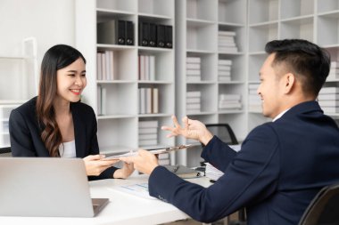 Zeki ve profesyonel erkek yönetici, bayan asistanıyla çalışıyor. Mali raporları grafik kağıtları ve masaüstü bilgisayarlarla analiz et.