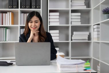 Asyalı kadın muhasebeci, istatistik ve analitik araştırma konseptiyle birlikte dizüstü bilgisayarla çalışan şirket çalışanlarının maaşlarını ödüyor..