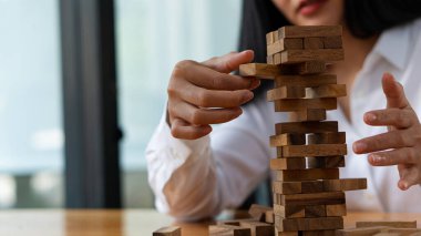 Genç bir kadın kuleye tahta bloklar yerleştiriyor, iş planı ve stratejisi, jengka ahşap bloklarıyla iş kurmak için risk kavramı