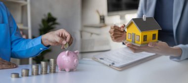 Domuz kumbarasında madeni paralar, ev almak için para biriktirmek için ahşap ev, tasarruf ve borç almak için finansal konsept. Yatay kesit.