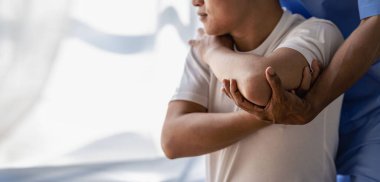 Hasta elini kapat ve klinikte yardım etmek için fizyoterapi uygula. Terapist yaralı adamı rotatör manşet germe metoduyla tedavi ediyor.