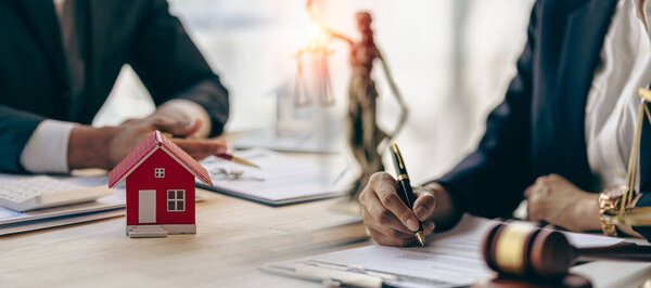 Real estate concept - judge and lawyer at auction with house model or lawyer with judge hammer to offset house insurance