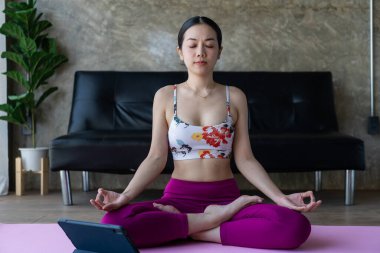 Genç Asyalı kadın sabah yatak odasında yoga yapıyor. Sağlıklı genç kadın sakin nefes alıyor ve evde dikey yoga yaparak meditasyon yapıyor.