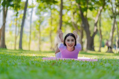 Asyalı bir kadın parkta yoga pozu veriyor. Genç sağlıklı kadın yoga egzersizi. Vücut, akıl ve sağlık için doğal çevrede yoga pozu. Rahatla konsept.
