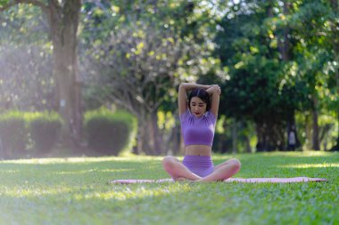 Asyalı bir kadın parkta yoga pozu veriyor. Genç sağlıklı kadın yoga egzersizi. Vücut, akıl ve sağlık için doğal çevrede yoga pozu. Rahatla konsept.