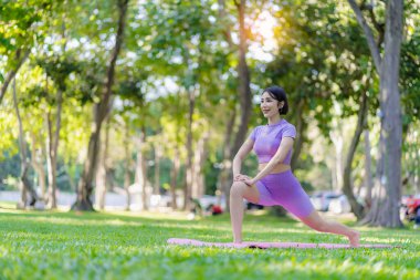 Asyalı bir kadın parkta yoga pozu veriyor. Genç sağlıklı kadın yoga egzersizi. Vücut, akıl ve sağlık için doğal çevrede yoga pozu. Rahatla konsept.