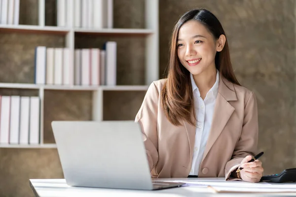 stock image Beautiful asian businesswoman working with laptop and financial documents on desk, company employee holding accounting documents Checking financial data or market reports working in the office.