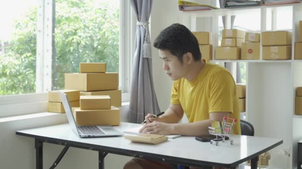 Азіатський Молодий Чоловік Продає Онлайн Вдома Коробкою Ноутбуком Приймає Замовлення — стокове відео