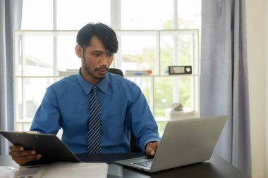 Analizcilerle çalışan genç Afrikalı bir adam güzel bir iş yerinde dizüstü bilgisayarı ve finansal rapor analiz konsepti belgesiyle oturuyor. aylık hesap