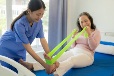 Asyalı kadın fizyoterapist yaşlı kadının bacak kaslarını esnetmesine ve spor salonu sağlık konseptinde bacak veya bacak rehabilitasyonu yapmasına yardım ediyor.