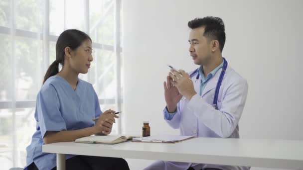亚洲女性患者坐在桌旁 听一位医学专业人员用听诊器解释医院病房健康医学概念中的诊断 — 图库视频影像