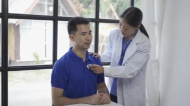Steteskop Asyalı hasta kullanarak hastanın solunum hızını ya da nabzını ölçen doktor sağlığını kontrol ederken, kadın doktor kalp atışlarını duymak için stetoskop kullanıyor..