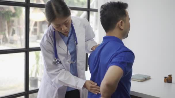 女性医師が男性の患者の理学療法を手持ちリフトで行い アジアの女性理学療法士が働き 患者の手を保護するのを助け 患者はクリニックでストレッチをします — ストック動画