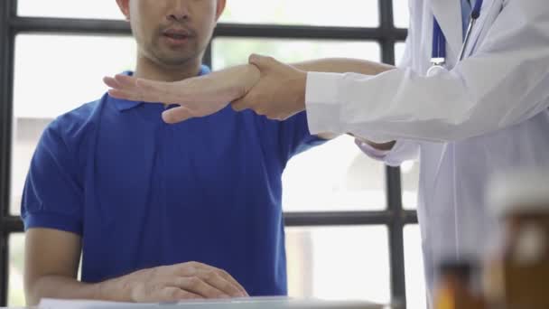 Lekarz Prowadzący Fizjoterapię Męską Podnoszeniem Ręki Fizjoterapeutka Azjatycka Pracująca Pomagająca — Wideo stockowe