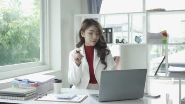 Bilgisayarla çalışan Asyalı çekici bir iş kadını ve finansal belgeleri hesaplayarak masaya yatırıyor. Bilgisayarınızı ve hesap makinenizi kullanarak evrak işlerini düzenliyorsunuz..
