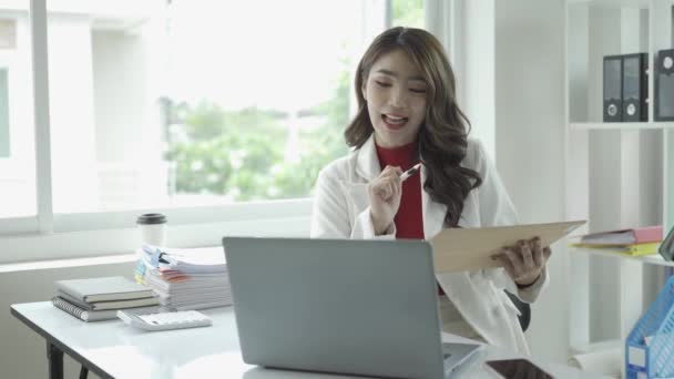 ラップトップで作業し 財務報告書を計算して表の財務書類をチェックする魅力的なアジアのビジネス女性あなたのラップトップと計算機を援助として使用して書類を整理する — ストック動画